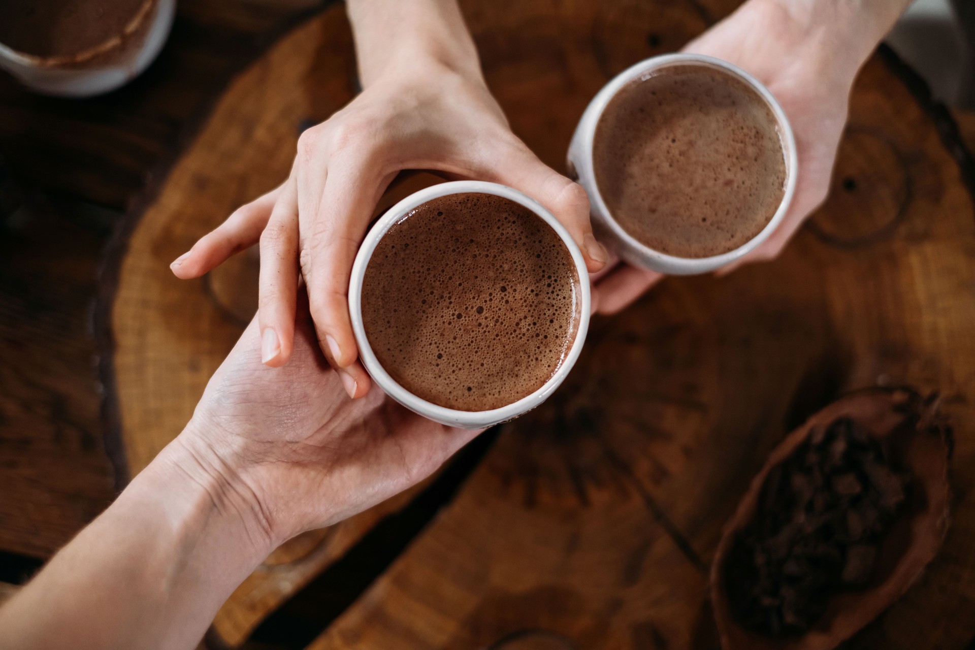 Person giving ceremonial cacao in cup. chocolate drink top view